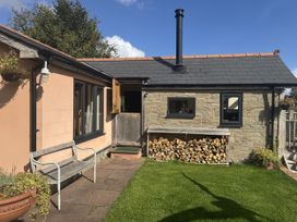 An outdoor view of a cabin with a wood pile and garden at The Hideout in Llangrove