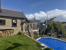 A house with a wooden deck, metal sculpture, and a pool at The Hideout in Llangrove