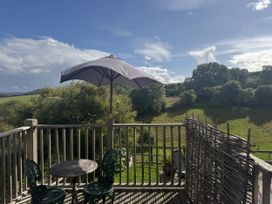 An outdoor area with a table and chairs under an umbrella at The Hideout in Llangrove