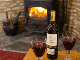 A wine bottle and two glasses on a table with a fireplace in the background at The Coach House in Kingston