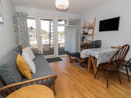 A living room with a sofa, table, and bookshelf at 56C South Snowdon Wharf in Porthmadog