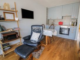 A kitchen with a dining table and an armchair at 56C South Snowdon Wharf in Porthmadog