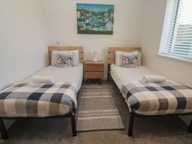 A bedroom with two beds and a bedside table at Sandpiper in Perranporth