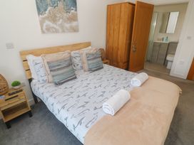 A bedroom with a bed and a wardrobe at Sandpiper in Perranporth