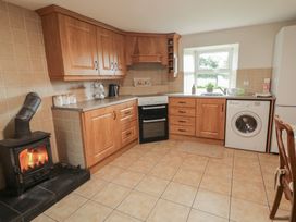 A kitchen with an oven, stove, sink, and washing machine at Shaws Hill Farmhouse Kells, County Antrim