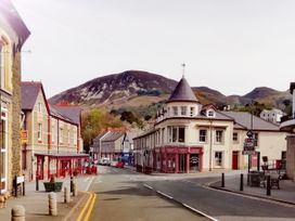 A street with buildings and parked cars near hills at Llys Madoc The Top Flat in Penmaenmawr
