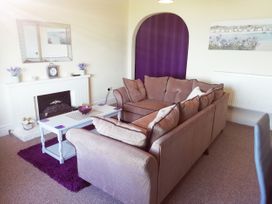 A living room with two sofas a white coffee table and a fireplace with a mirror above at Llys Madoc The Top Flat in Penmaenmawr