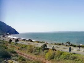 A view of the coastline with a road and railway tracks near the sea at Llys Madoc The Top Flat in Penmaenmawr