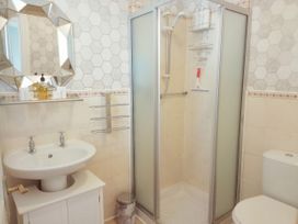 A bathroom with a sink cabinet mirror shower enclosure and toilet at Llys Madoc The Top Flat in Penmaenmawr