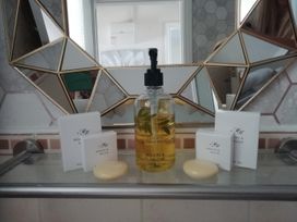 A bathroom sink area with a geometric mirror and Mason and Miller toiletries at Llys Madoc, The Top Flat in Penmaenmawr