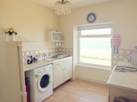 A kitchen with a washing machine sink stove and window showing a view at Llys Madoc The Top Flat in Penmaenmawr