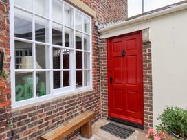 An outdoor area with a red front door and a bench at 20A St Hilda's in Whitby