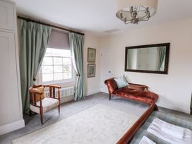 A bedroom with a window, curtains, chair, sofa, and mirror at 20A St Hilda's in Whitby