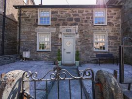 Stone front of a house with four windows a central door two potted plants a bench and an iron gate at Yr Hen Dy Capel in Blaenau Ffestiniog