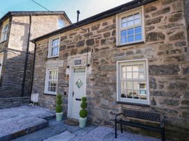 Stone front exterior of a house with white framed windows a white door two potted topiary plants and a black bench at Yr Hen Dy Capel in Blaenau Ffestiniog