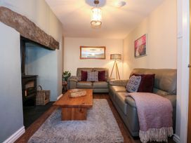 A living room with two sofas a wooden coffee table a rug a floor lamp and a fireplace at Yr Hen Dy Capel in Blaenau Ffestiniog