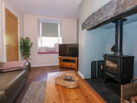 A living room with a wood stove and a television on a wooden stand at Yr Hen Dy Capel in Blaenau Ffestiniog