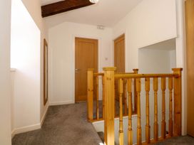A hallway with carpeted floor wooden doors a stair railing and a wall mirror at Yr Hen Dy Capel in Blaenau Ffestiniog