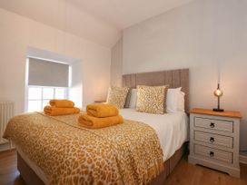A bedroom with a double bed a patterned bedspread folded towels a bedside table and a lamp at Yr Hen Dy Capel in Blaenau Ffestiniog