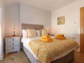 A bedroom with a bed with yellow patterned bedding and towels with bedside tables and lamps at Yr Hen Dy Capel in Blaenau Ffestiniog