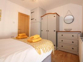 A bedroom with a bed, wardrobe, dresser, round mirror, and yellow towels on the bed at Yr Hen Dy Capel in Blaenau Ffestiniog