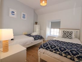 A bedroom with two single beds with patterned blankets a bedside table with a lamp a white chest of drawers and a window with a blind at Yr Hen Dy Capel in Blaenau Ffestiniog