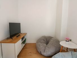 A small living area with a television on a cabinet a bean bag chair a small table with a flower pot at Yr Hen Dy Capel in Blaenau Ffestiniog