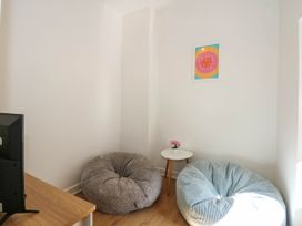 A corner of a room with two bean bags a small round table with a flower pot a wall art and a television on a wooden table at Yr Hen Dy Capel in Blaenau Ffestiniog