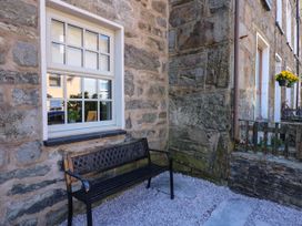 A metal bench next to a window on a stone wall exterior at Yr Hen Dy Capel in Blaenau Ffestiniog