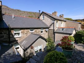 Exterior of stone and stucco houses with slate roofs and potted plants on a gravel area at Yr Hen Dy Capel in Blaenau Ffestiniog