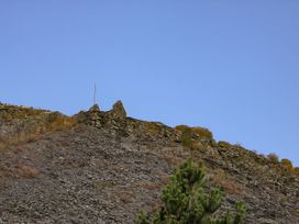 A rocky hillside with scattered vegetation and a small stone structure at the top at Yr Hen Dy Capel in Blaenau Ffestiniog