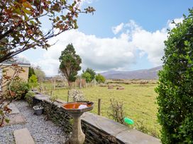 A garden view with a birdbath and trees at Glyn Morfa in Harlech
