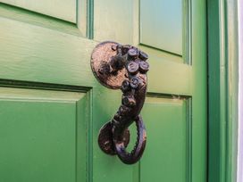 A green door with a decorative metal knocker at Cobbles House, Whitby