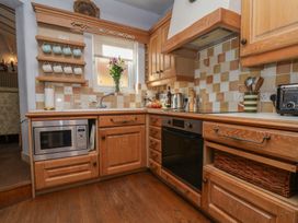 A kitchen with wooden cabinets and appliances at Cobbles House in Whitby