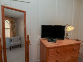 A bedroom with a dresser and TV at Cobbles House in Whitby