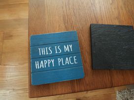 A blue coaster with text on a wooden table at Damson Cottage in Whitby