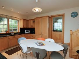 A kitchen with wooden cabinets and a round table at Damson Cottage in Whitby