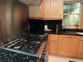 A kitchen with a stove and cabinets at Damson Cottage in Whitby