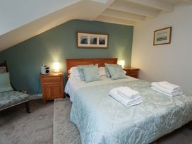A bedroom with a bed and a chair at Damson Cottage in Whitby