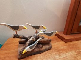 A decorative arrangement of wooden birds on a base at Damson Cottage in Whitby