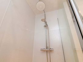 A shower with a fixed and handheld shower head at Damson Cottage in Whitby