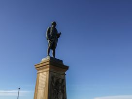 A statue on a pedestal with a plaque at Beachfront in Whitby