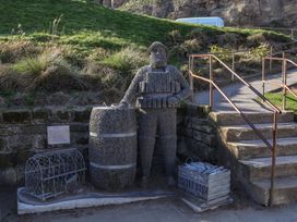 A wire sculpture of a man standing with a barrel and basket at Beachfront in Whitby