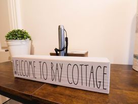 A welcome sign on a table with a plant and a water bottle at Bay Cottage The Bay - Filey