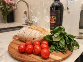 A kitchen countertop with bread cherry tomatoes basil wine bottle and two wine glasses at The Riddle in Whitby