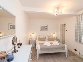 A bedroom with a double bed with pillows and folded towels bedside tables and a dresser with mirror at The Riddle in Whitby
