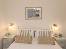 A bedroom with a bed flanked by two nightstands each with lamps and decor at The Riddle in Whitby