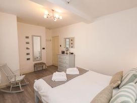 A bedroom with a bed with folded towels two dressers a rocking chair a wall mirror and small pictures at The Riddle in Whitby