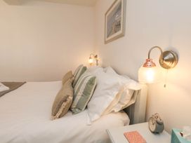 A bedroom with a bed with pillows and a bedside table with a clock and a tissue box at The Riddle in Whitby