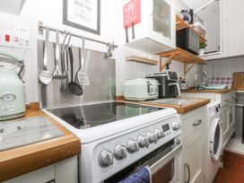A kitchen with a stove, kettle, and washing machine at Tan Yr Allt in Chwilog